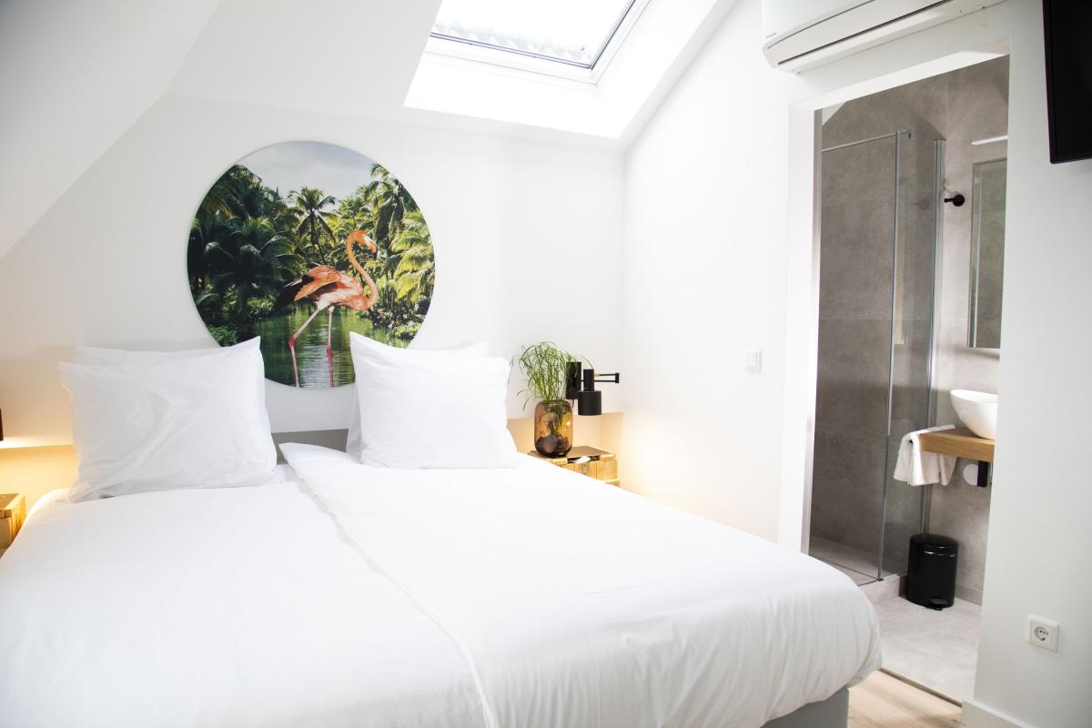 A light hotel room with a skylight, a small modern bathroom and a view on the city of Den Bosch